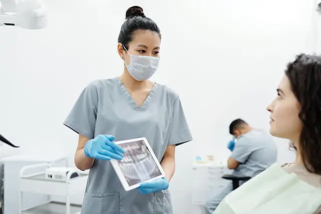 A dentist showing a patient a dental x-ray on a tablet